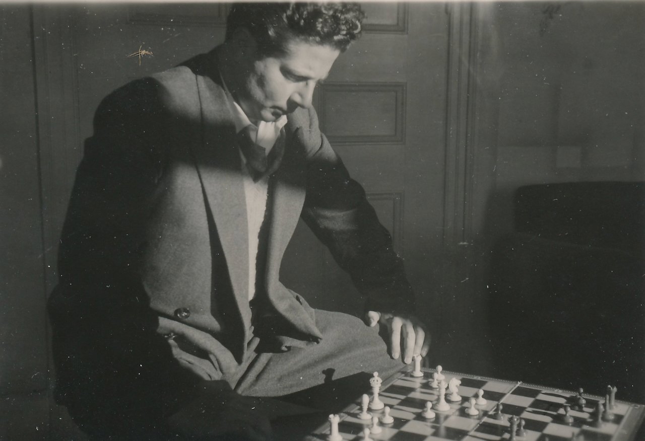 Man playing chess, focused and thoughtful, in a vintage black and white setting.